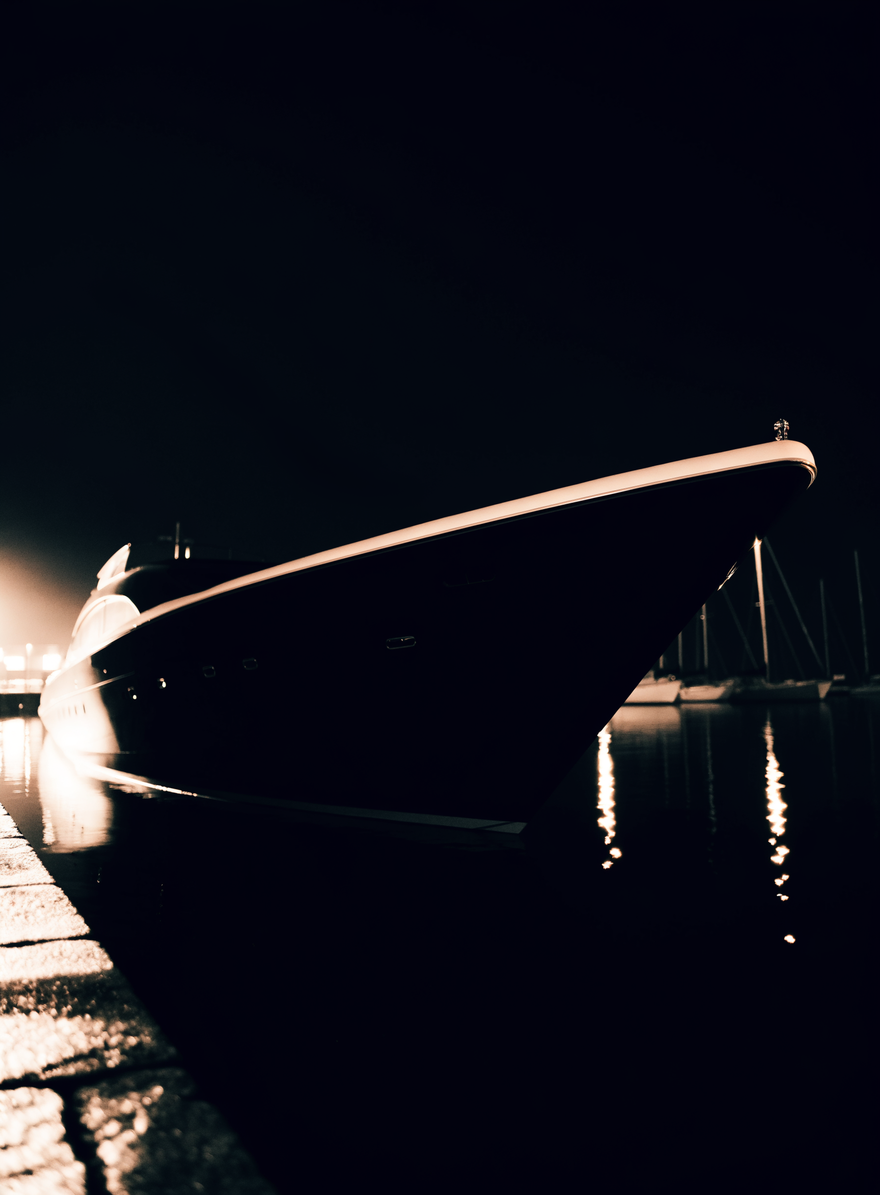 Yacht privé à quai la nuit, reflets champagne sur l'eau noire