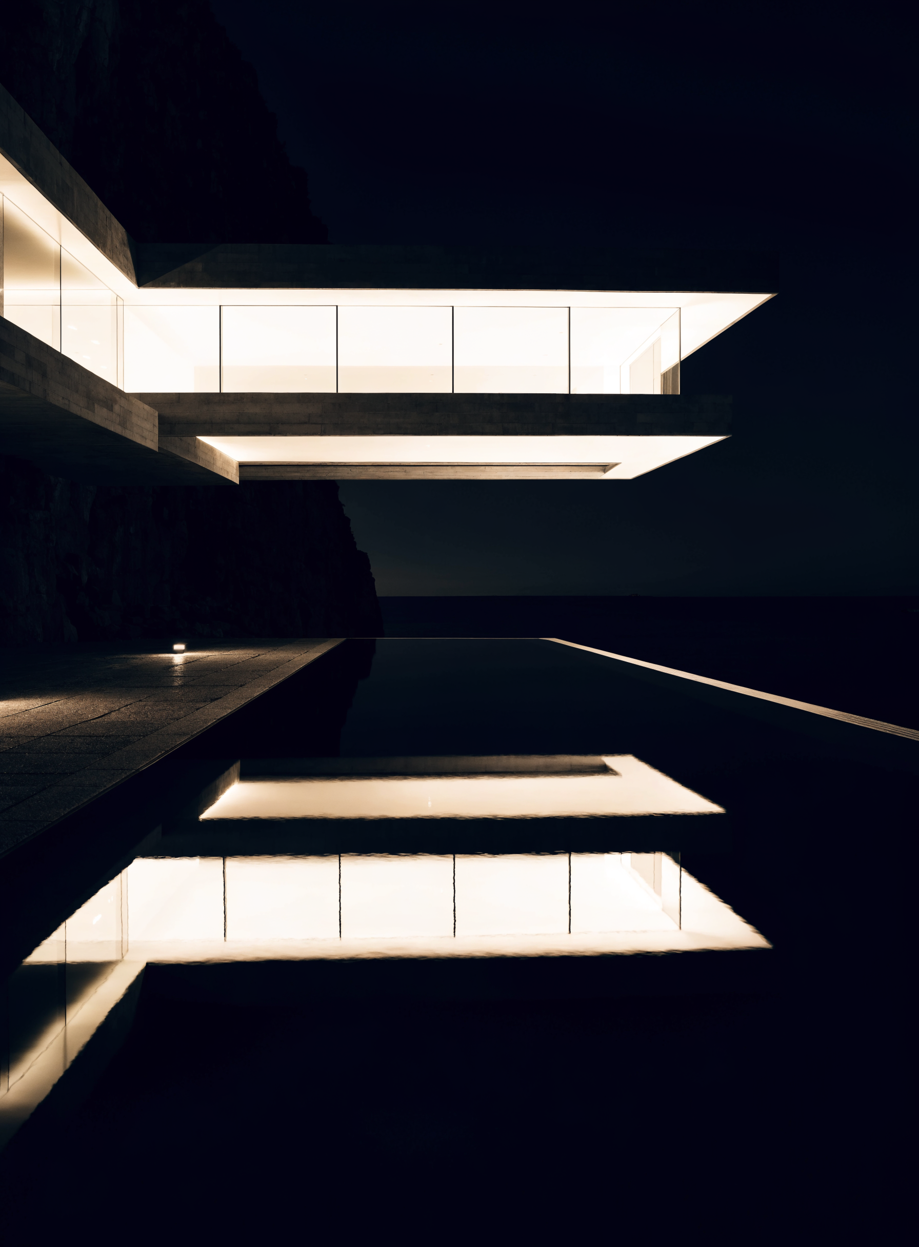 Villa contemporaine la nuit reflétée dans une piscine à débordement
