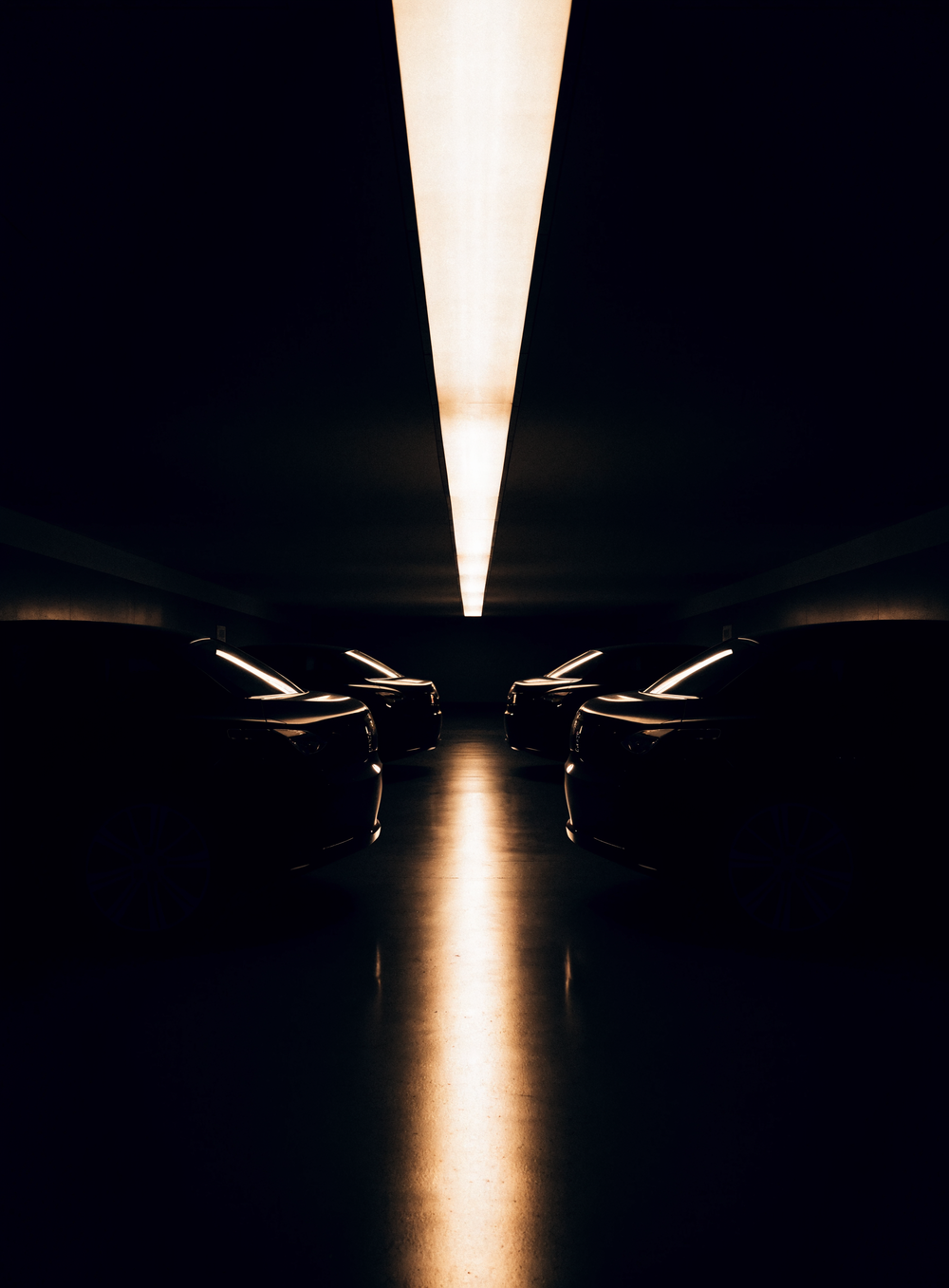Garage privé souterrain, rangée de voitures sombres sous un bandeau lumineux