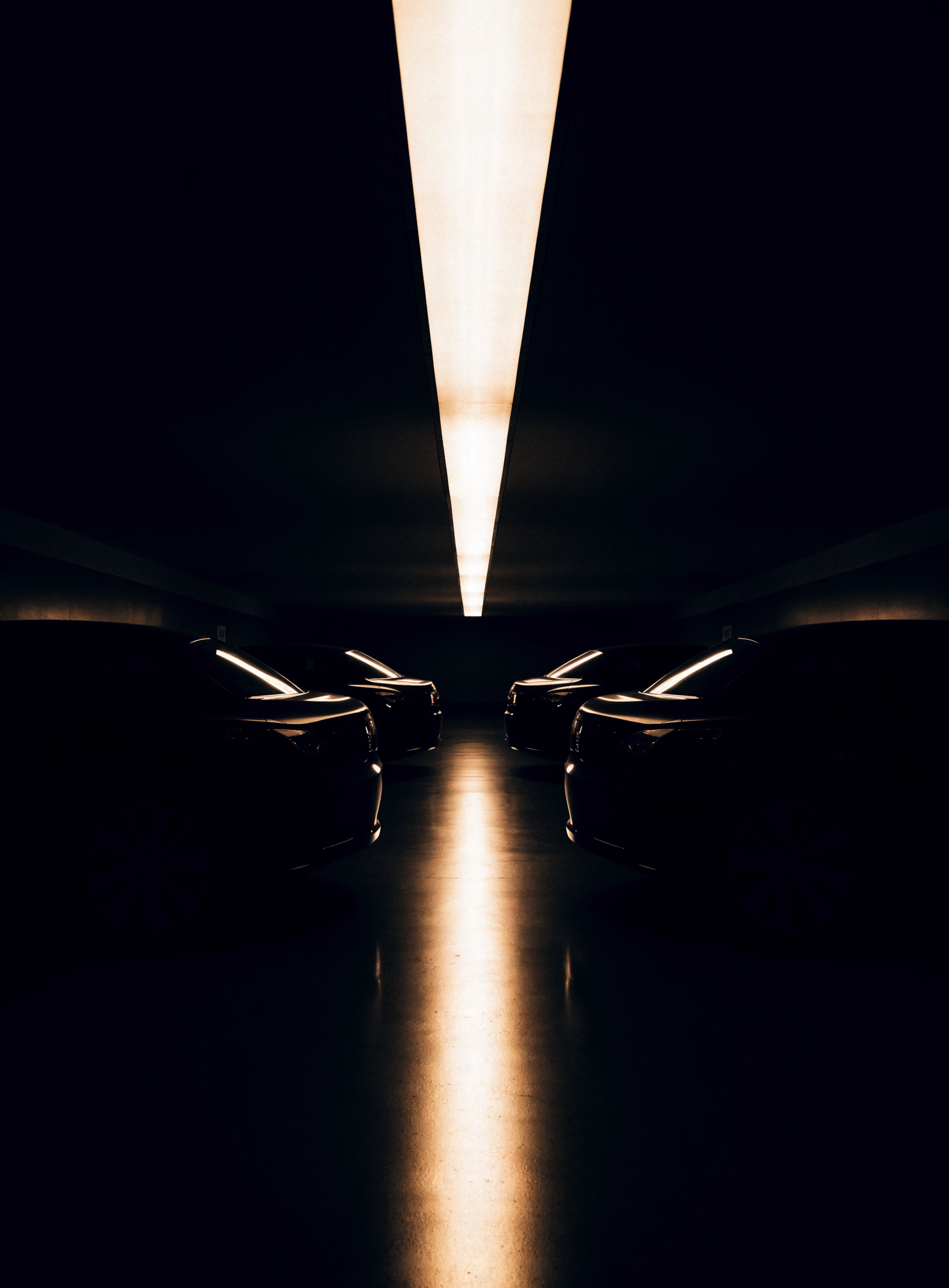 Garage privé souterrain, rangée de voitures sombres sous un bandeau lumineux