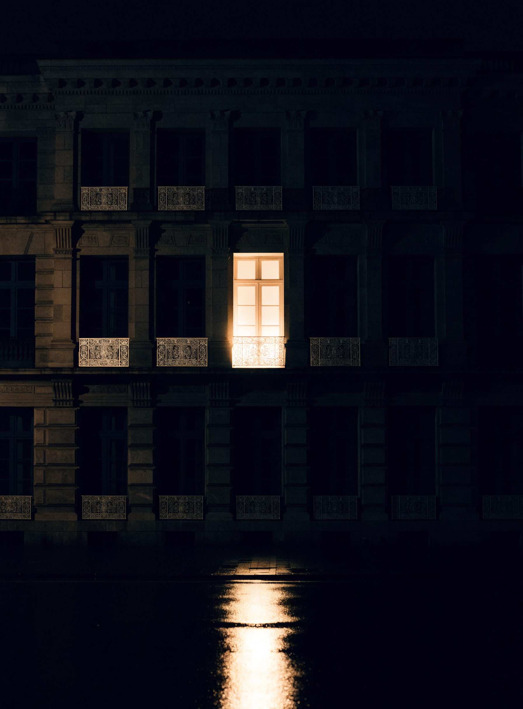 Façade de pierre la nuit, une seule fenêtre allumée