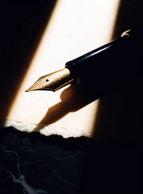Stylo plume à plume d'or posé sur une feuille de papier de coton vierge